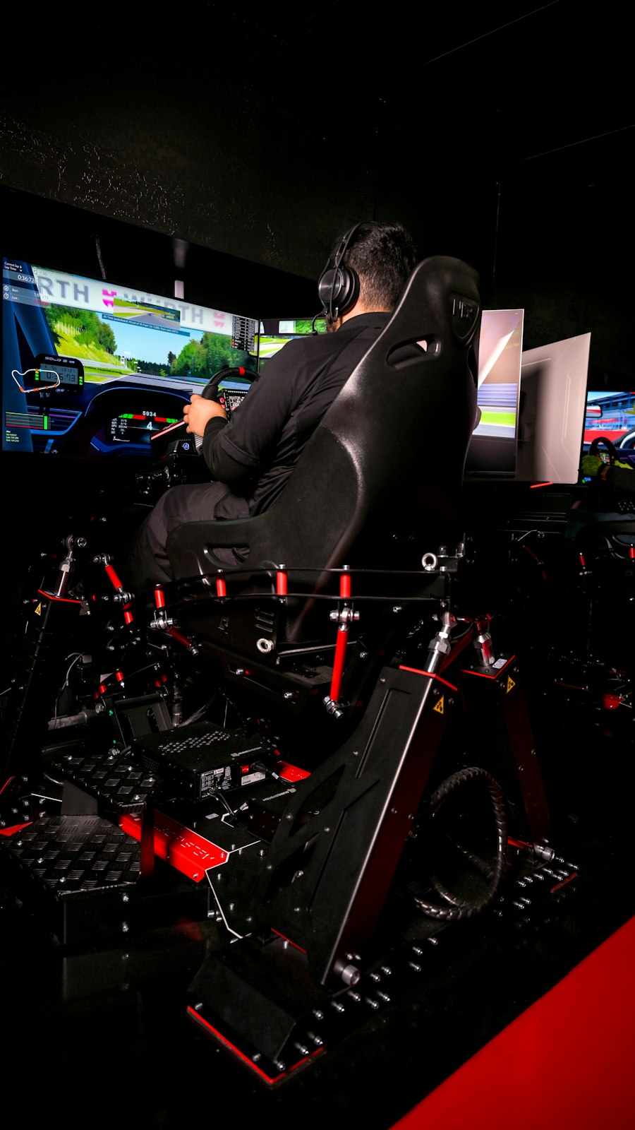 Driver at a sim racing rig with multiple screens